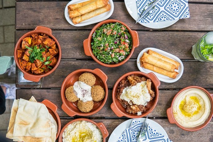 Schalen mit syrischem Essen darunter Falafel, Babaganoush, Humus und Fladenbrot im Waldcafé Saha.